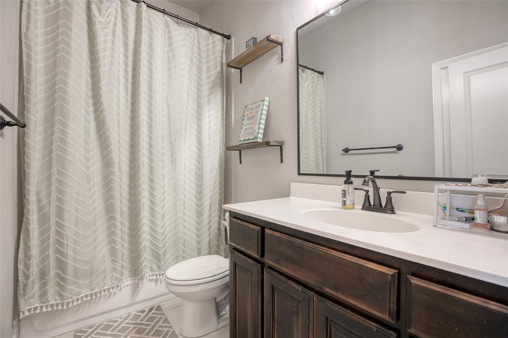 211 Rees Avenue Godley, TX 76044 - Photo 16 of 18 a bathroom with a sink a toilet and shower curtain