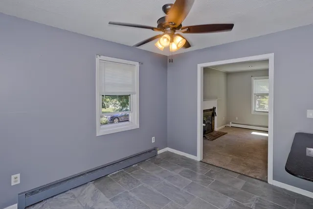 an empty room that has a window and a chandelier fan