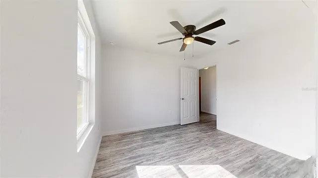 a view of empty room with wooden floor and ceiling fan