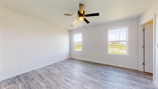 a view of empty room with wooden floor and fan