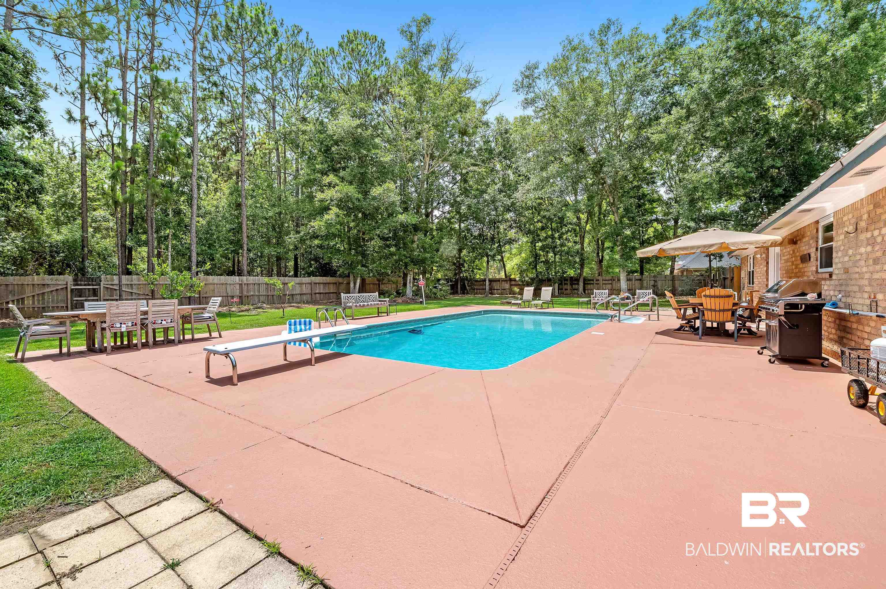 24551 Wolf Bay Drive Foley, AL 36535 - Photo 13 of 59 View of pool with a patio area, outdoor dining area, a diving board, a fenced backyard, and view of wooded area