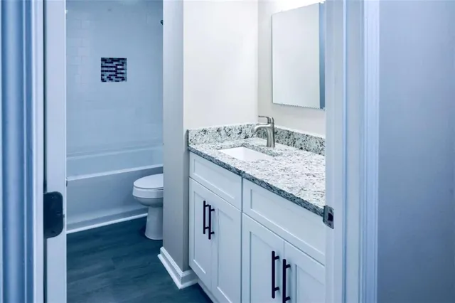 a bathroom with a granite countertop sink a toilet and shower