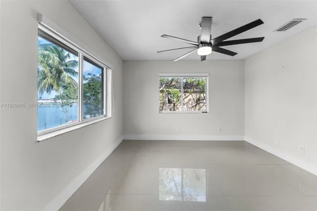an empty room with windows and ceiling fan