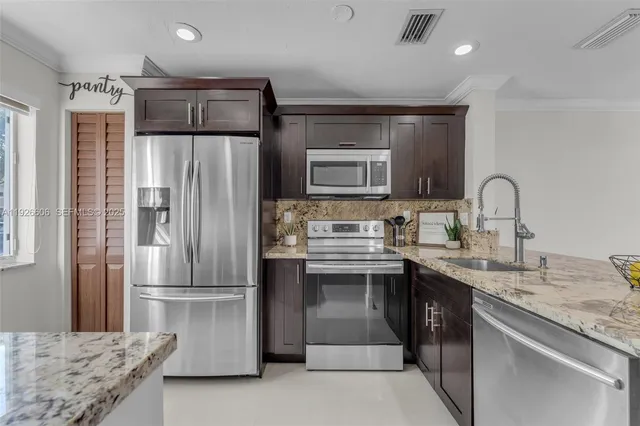 a kitchen with stainless steel appliances granite countertop a refrigerator sink and stove