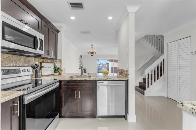 a kitchen with stainless steel appliances granite countertop a sink a stove and a microwave