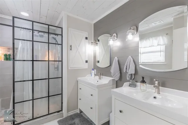 a bathroom with a double vanity sink mirror and shower