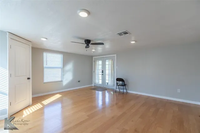 a view of empty room with wooden floor and fan