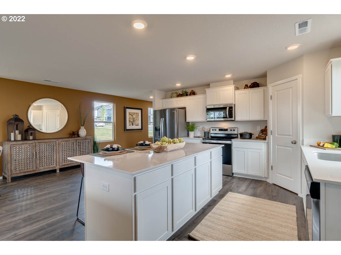 240 Northeast 28th Court Ridgefield, WA 98642 - Photo 11 of 32 a open kitchen with cabinets a sink and a stove with wooden floor