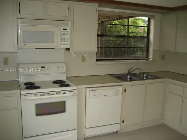 a kitchen with white cabinets and white appliances