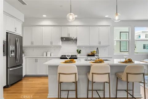 a kitchen with stainless steel appliances granite countertop a sink a stove a refrigerator cabinets and chairs