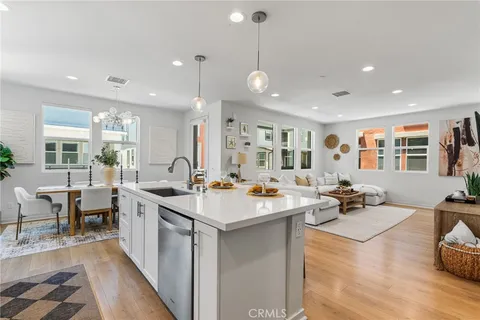 a room with stainless steel appliances kitchen island granite countertop a sink and white cabinets with wooden floor