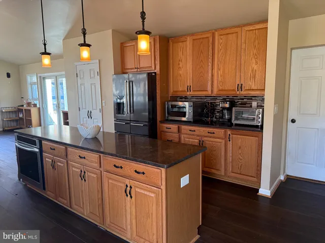 a kitchen with stainless steel appliances kitchen island granite countertop a stove a sink a refrigerator and wooden floor