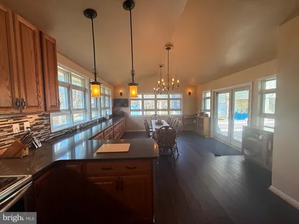 a view of a dining room and livingroom with furniture wooden floor a chandelier