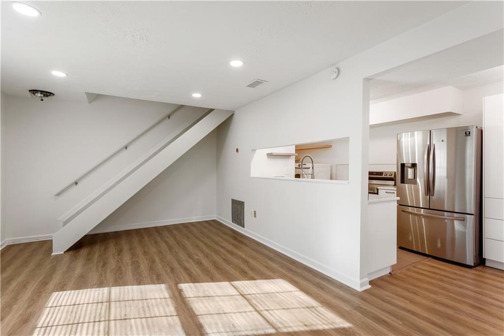 a view of a kitchen with refrigerator and wooden floor