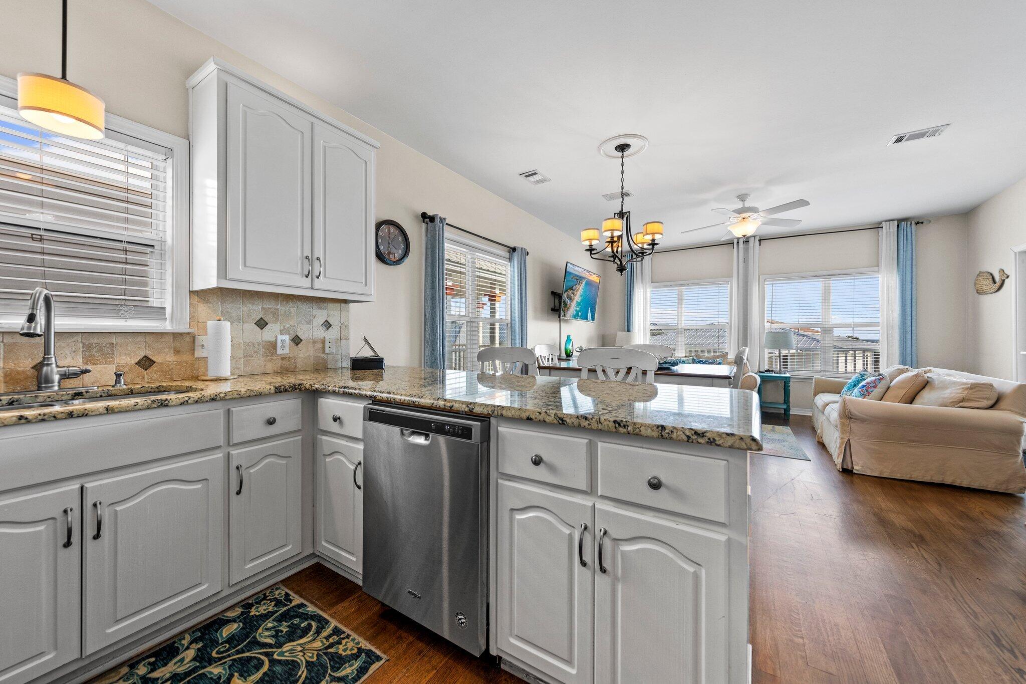 156 Emerald Dunes Circle Santa Rosa Beach, FL 32459 - Photo 9 of 43 a kitchen with kitchen island granite countertop a sink cabinets and wooden floor