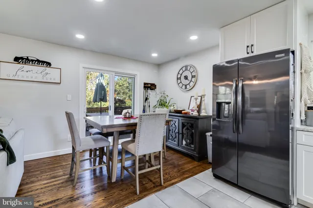a kitchen with stainless steel appliances granite countertop a dining table chairs refrigerator and sink