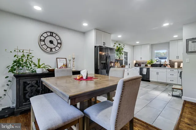a living room with stainless steel appliances furniture a clock and a view of kitchen