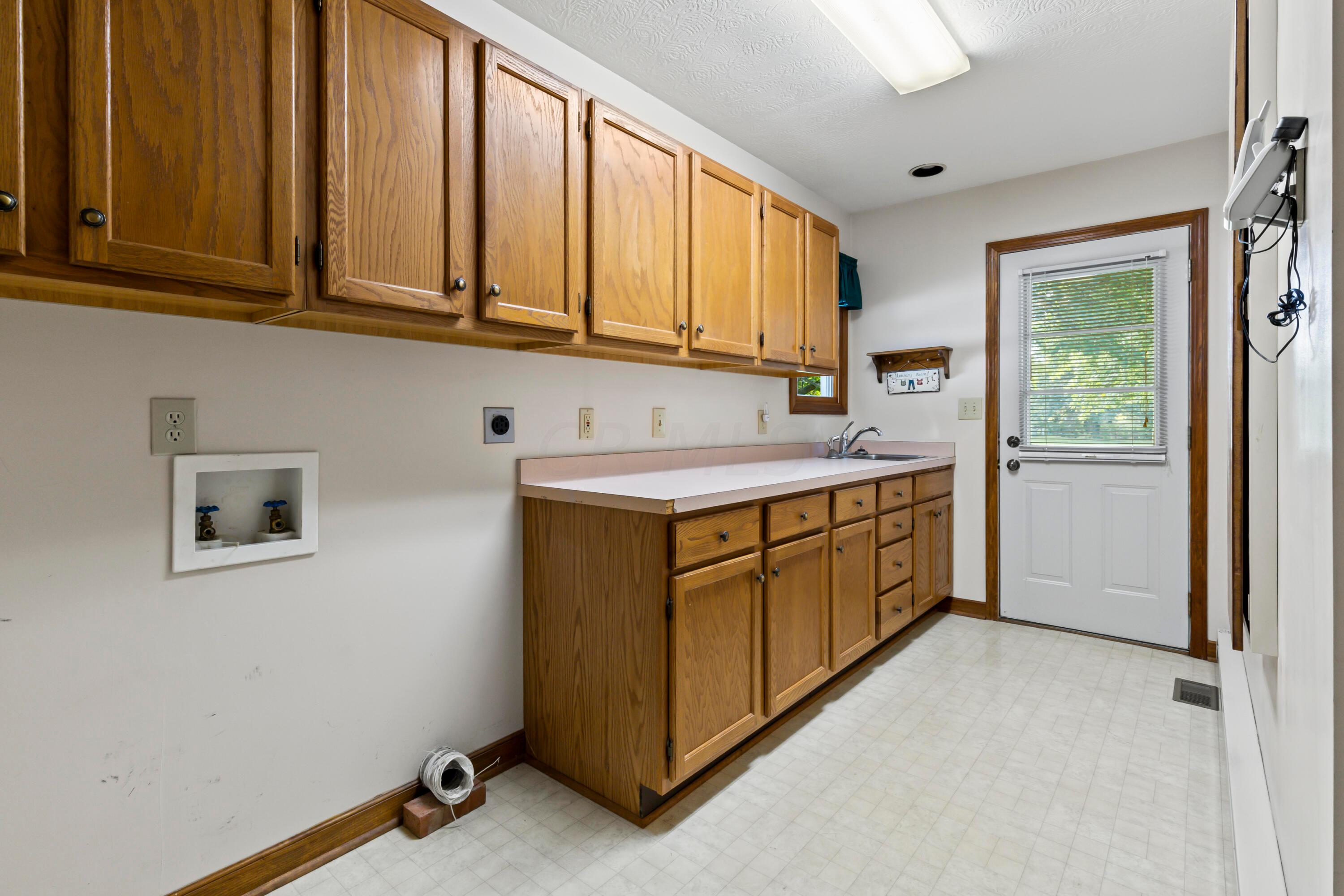 5764 Cheshire Road Galena, OH 43021 - Photo 20 of 59 • Neutral vinyl flooring
• Tan painted walls
• Wall cabinets
• Enclosed & extended vanity
• Single bowl, stainless steel
sink
• Built-in ironing board
• Electric dryer hookup
• Rear service door
• Step-in closet
