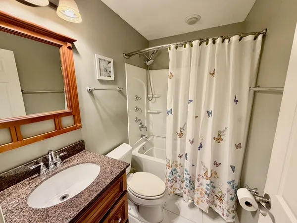 a bathroom with a granite countertop sink toilet a mirror a vanity and shower