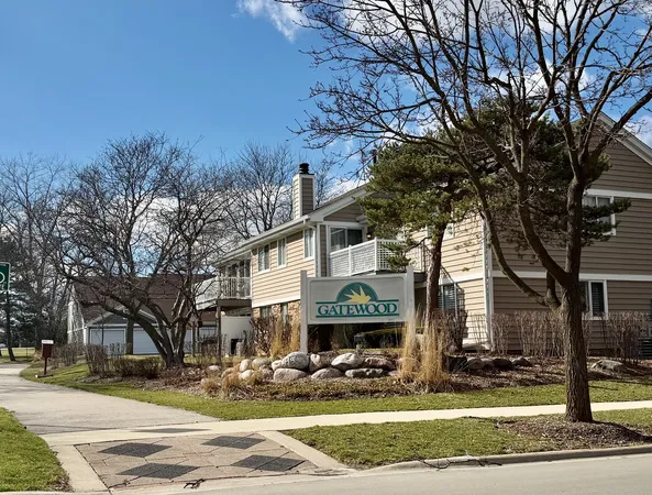 a front view of a building with garden and trees
