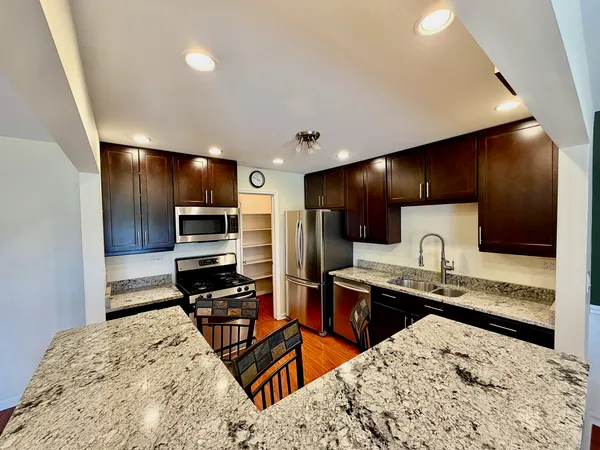 a kitchen with stainless steel appliances kitchen island granite countertop a sink refrigerator and cabinets
