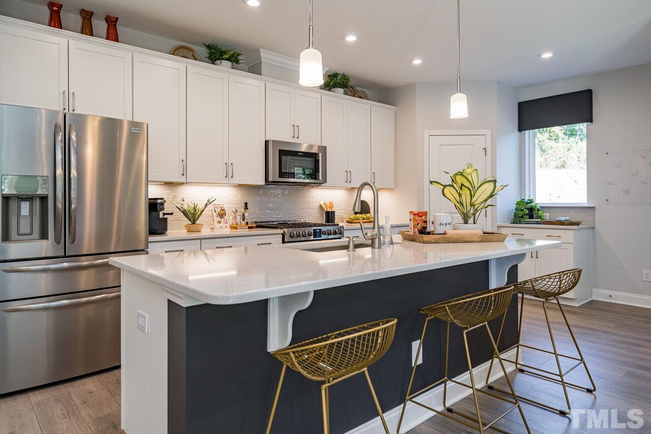3115 Dunnock Drive, Unit 2 Durham, NC 27713 - Photo 8 of 24 a kitchen with kitchen island granite countertop a sink stove and refrigerator