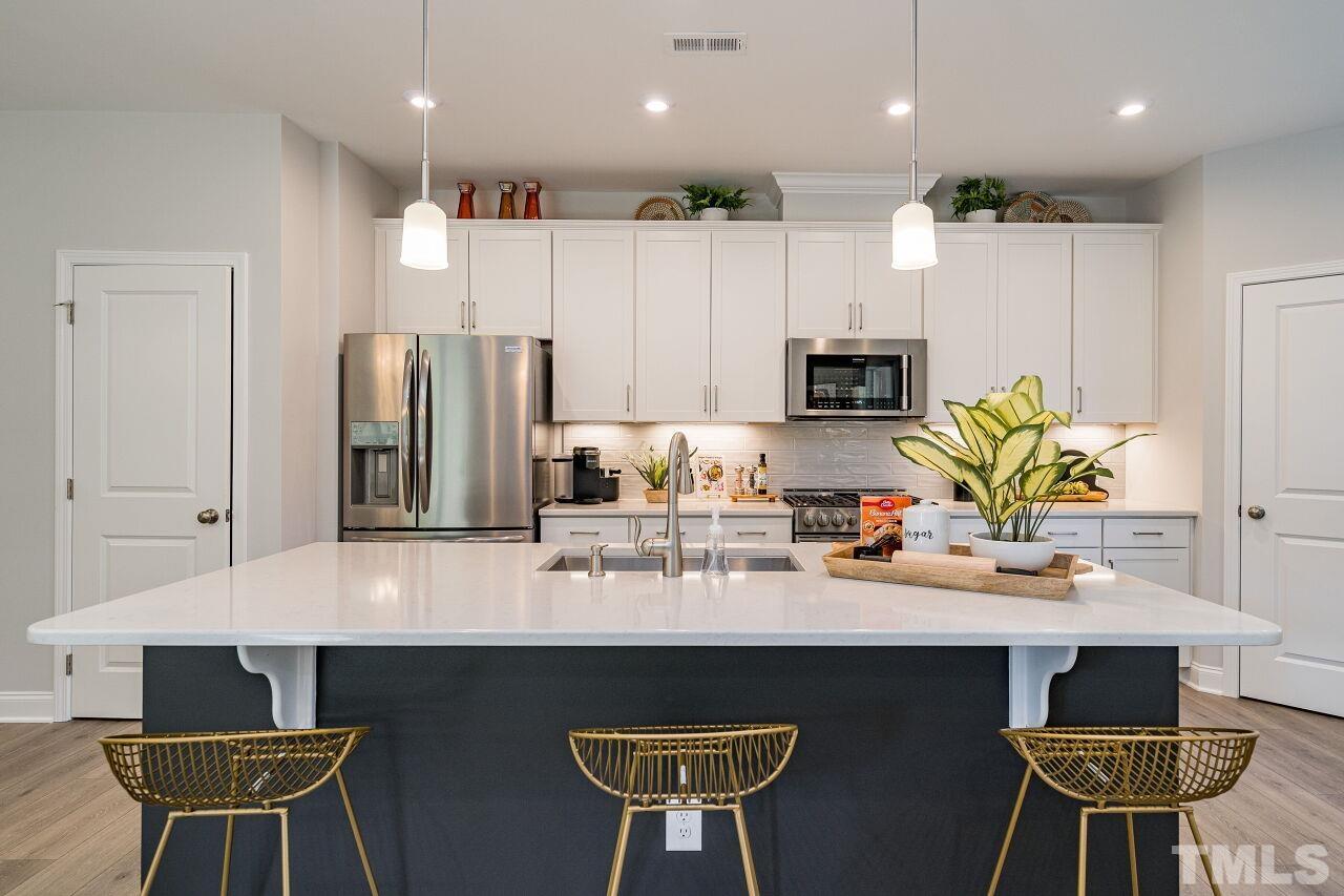 3115 Dunnock Drive, Unit 2 Durham, NC 27713 - Photo 9 of 24 a kitchen with stainless steel appliances a dining table chairs refrigerator and microwave
