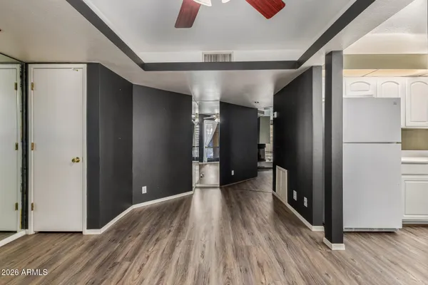 a view of empty room with wooden floor and fan