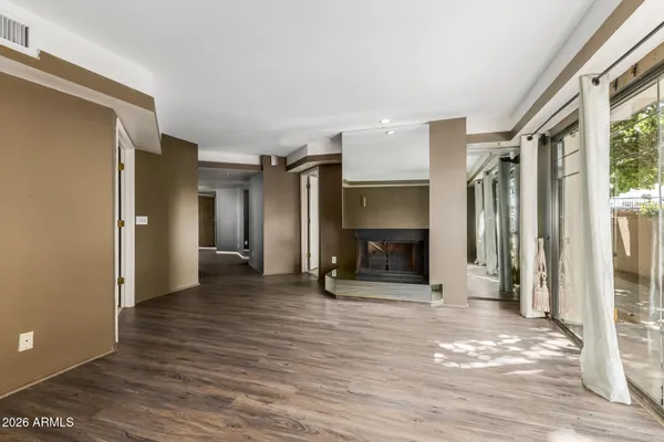 a view of an empty room with wooden floor a fireplace and a window