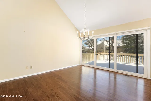 a view of an empty room with window and wooden floor