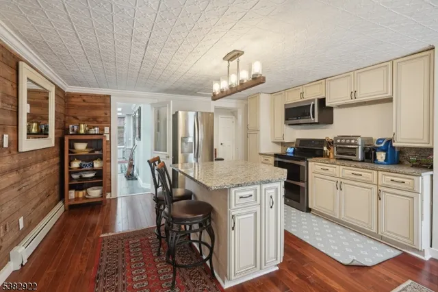 a kitchen with stainless steel appliances granite countertop a stove top oven a sink dishwasher and a dining table with wooden floor