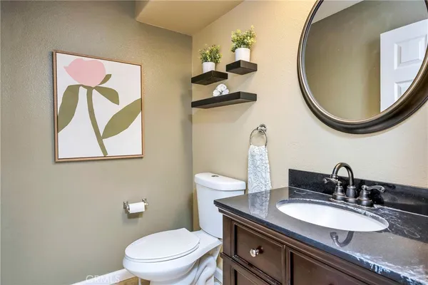 a bathroom with a granite countertop toilet a sink and a mirror