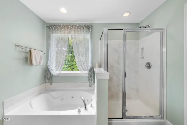 a bathroom with a bathtub a shower and a window