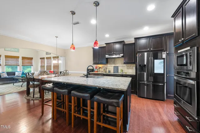 a kitchen with stainless steel appliances granite countertop a table chairs stove and refrigerator