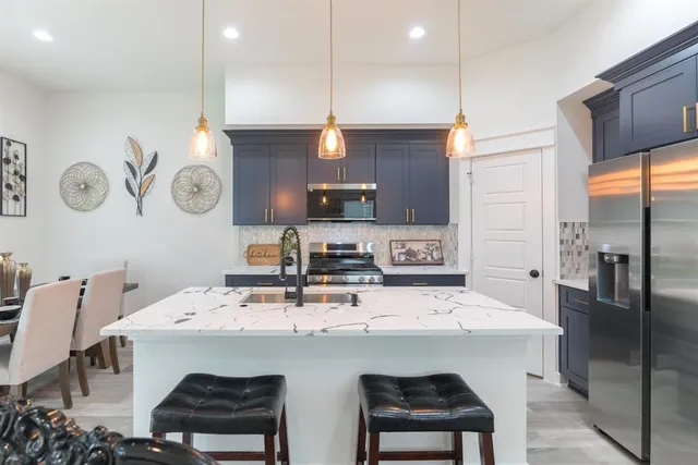 a kitchen with a sink a center island a stove cabinets and a dining table