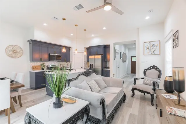 a very nice looking open dining room with kitchen island stainless steel appliances furniture a fireplace and a chandelier