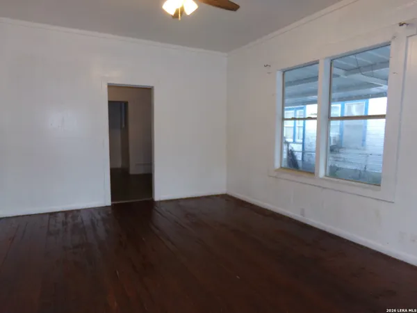 a view of an empty room with wooden floor and a window
