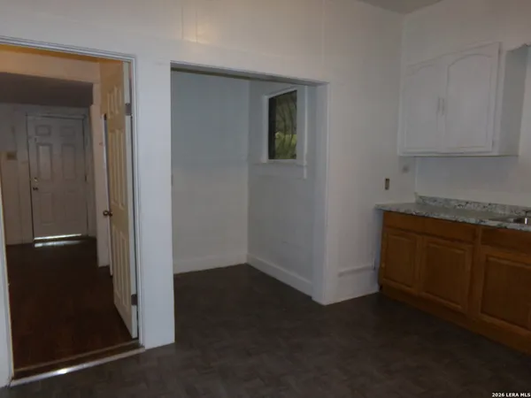an empty room with wooden floor closet and windows