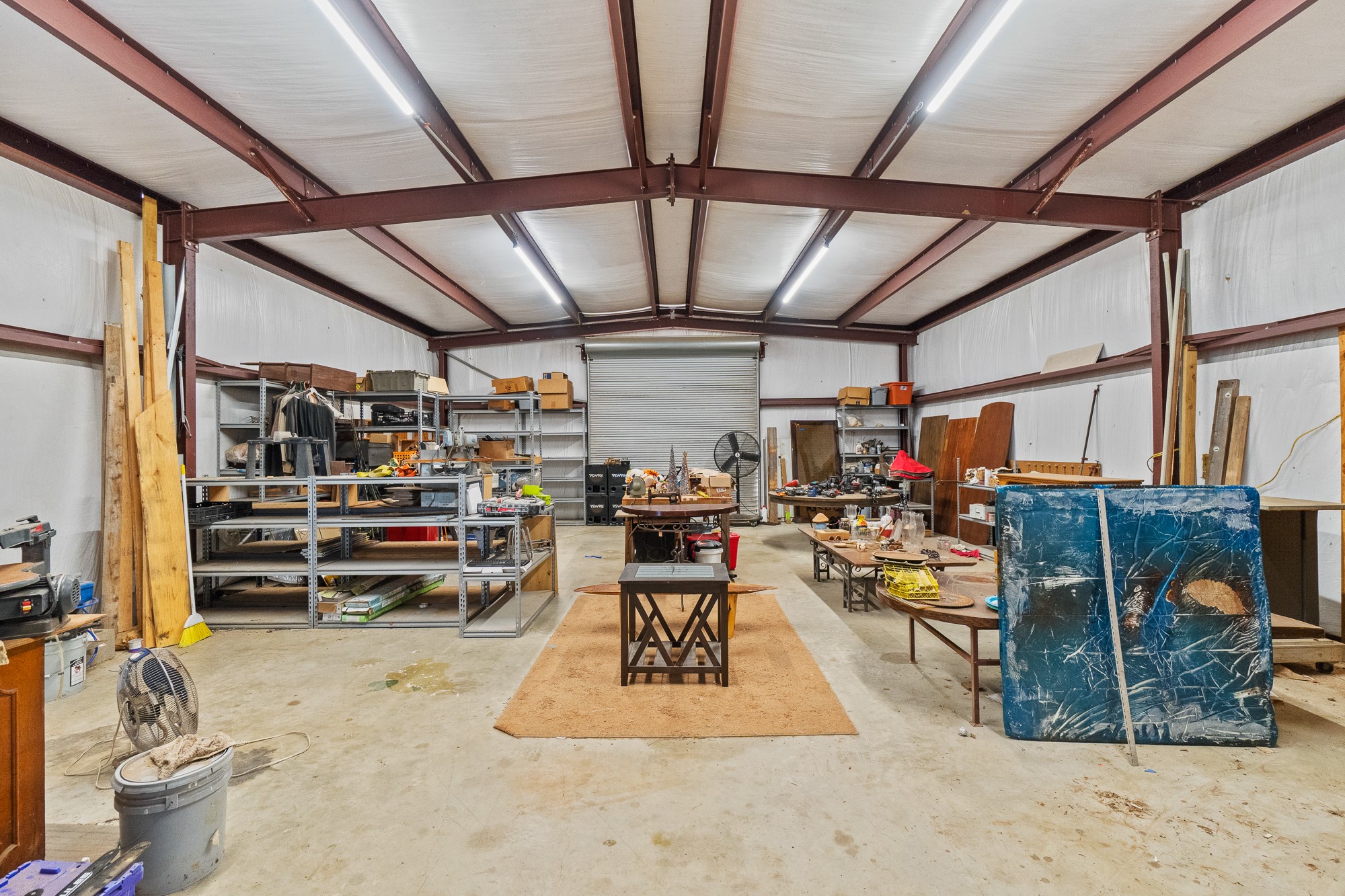 1951 Dowdy Road Seguin, TX 78155 - Photo 23 of 40 Steel beams span the ceiling of this massive concrete-floored workshop with a roll-up bay door.