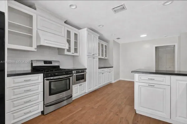 a kitchen with white cabinets and stainless steel appliances