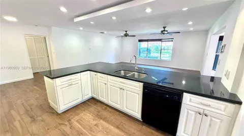a kitchen with granite countertop white cabinets white appliances and a sink