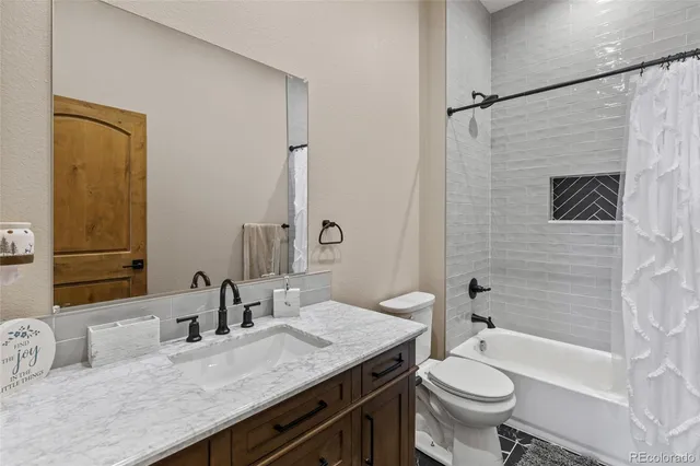 a bathroom with a granite countertop sink a toilet a mirror a bathtub and shower