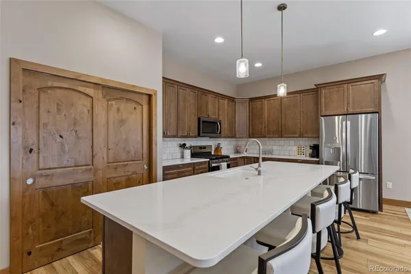 a kitchen with stainless steel appliances a table chairs refrigerator and wooden cabinets