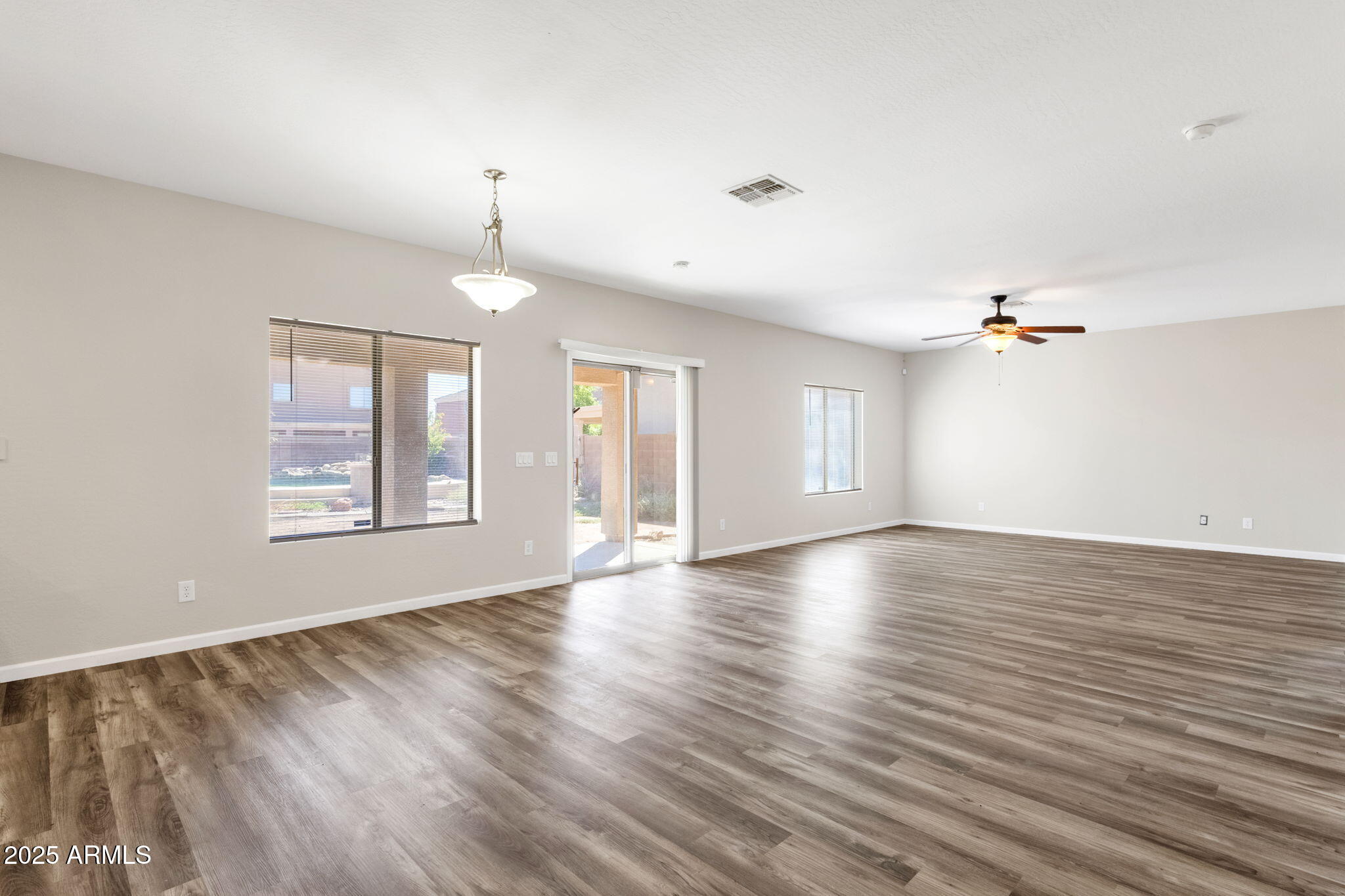 43003 West Magnolia Road Maricopa, AZ 85138 - Photo 10 of 32 an empty room with wooden floor ceiling fan and windows