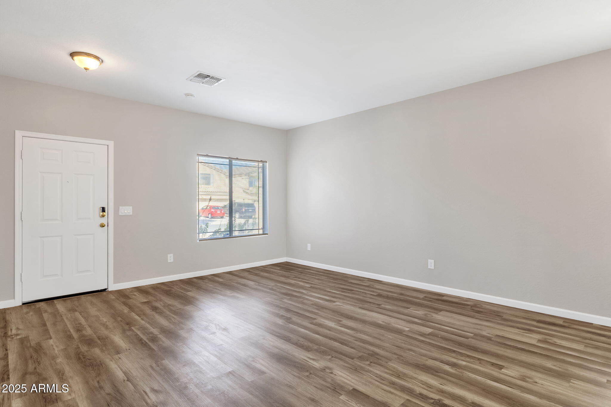 43003 West Magnolia Road Maricopa, AZ 85138 - Photo 4 of 32 a view of an empty room with wooden floor and a window