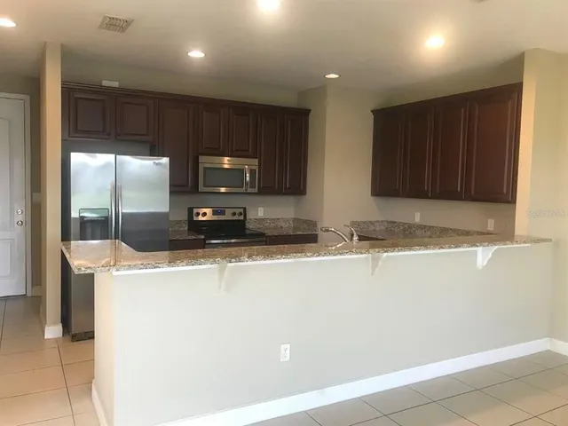 a view of kitchen with stainless steel appliances wooden floor and large window