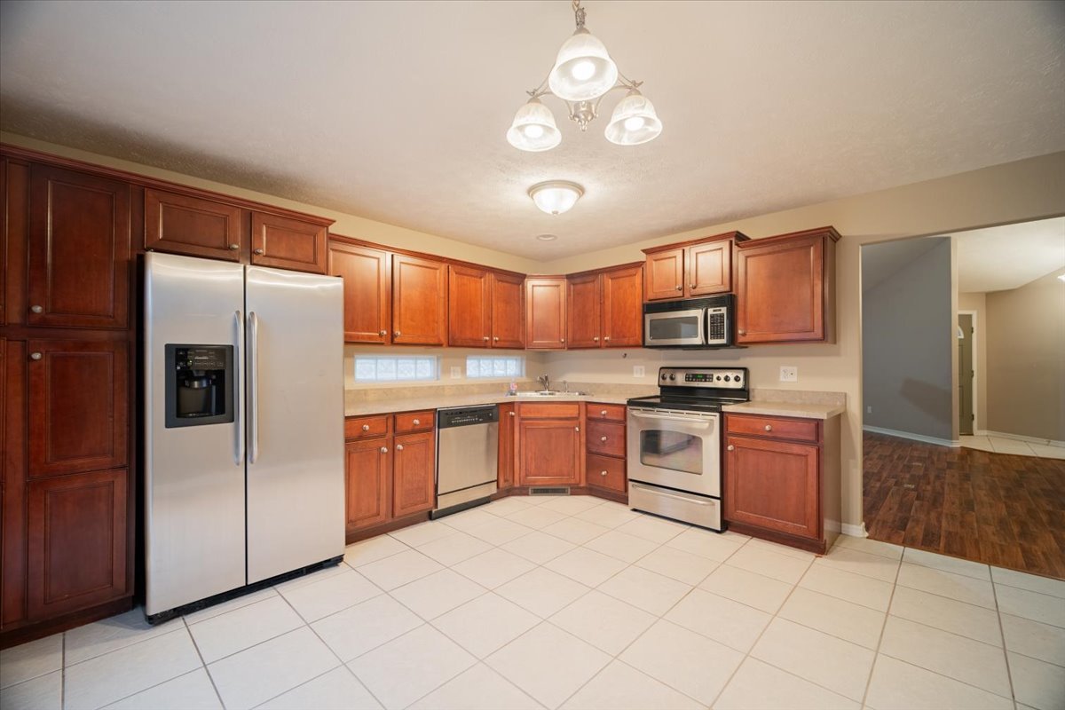 2885 East Raab Road Normal, IL 61761 - Photo 9 of 35 a kitchen with stainless steel appliances granite countertop a refrigerator a stove top oven a sink dishwasher and a refrigerator with wooden cabinets
