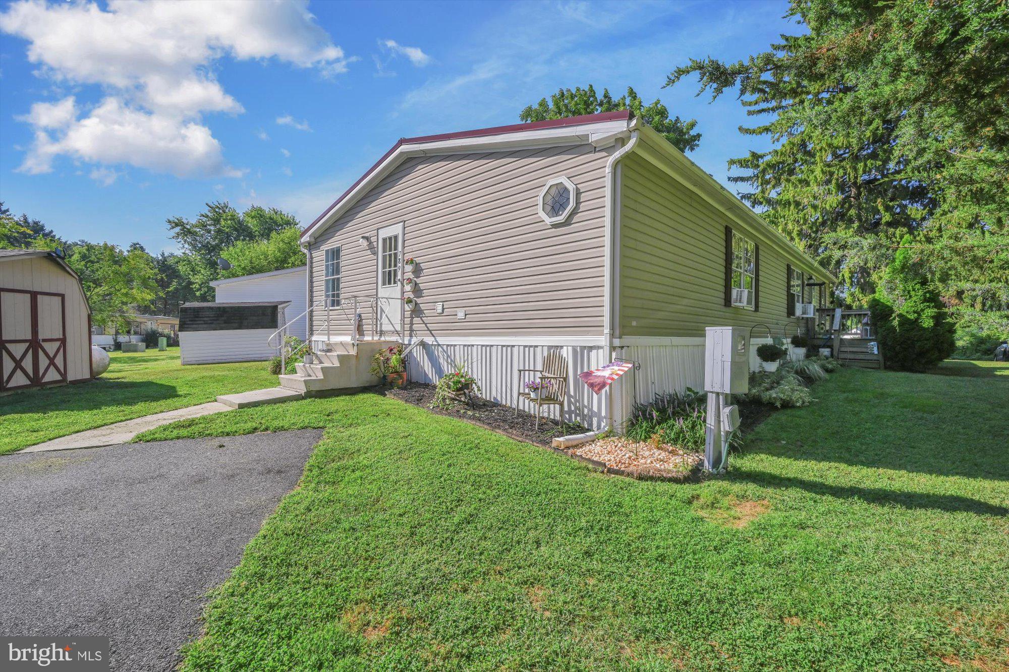 a backyard of a house with plants and large tree