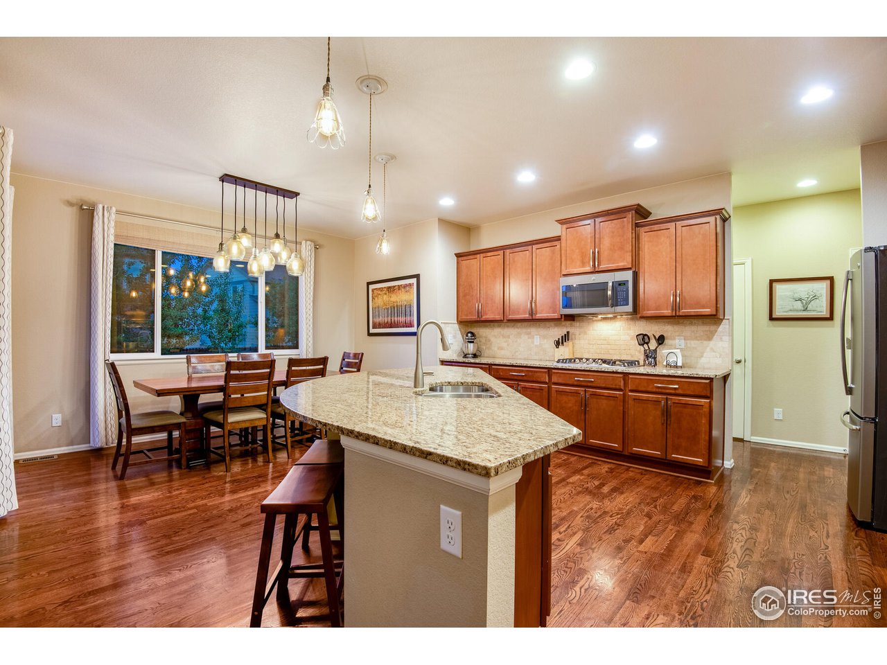 5762 Graphite Street Timnath, CO 80547 - Photo 12 of 27 a open kitchen with stainless steel appliances granite countertop a stove top oven a sink dishwasher a dining table and chairs with wooden floor