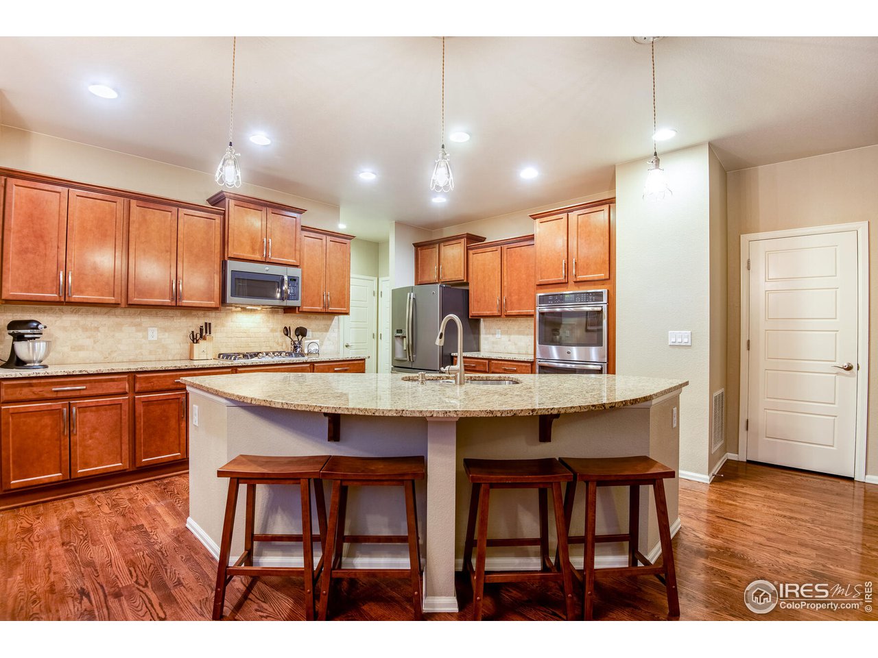 5762 Graphite Street Timnath, CO 80547 - Photo 15 of 27 a kitchen with kitchen island granite countertop wooden cabinets and center island